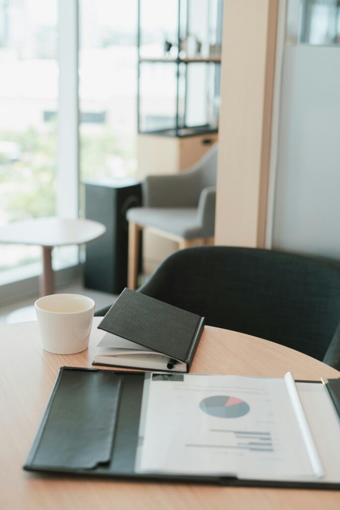 A modern office setting featuring a notebook, coffee cup, and documents on a wooden desk.